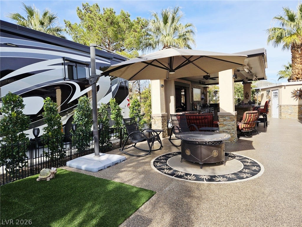 8175 Arville Street, #287, Las Vegas, NV 89139 A spacious concrete patio features an integrated outdoor kitchen and pavilion structure alongside tall palm trees.