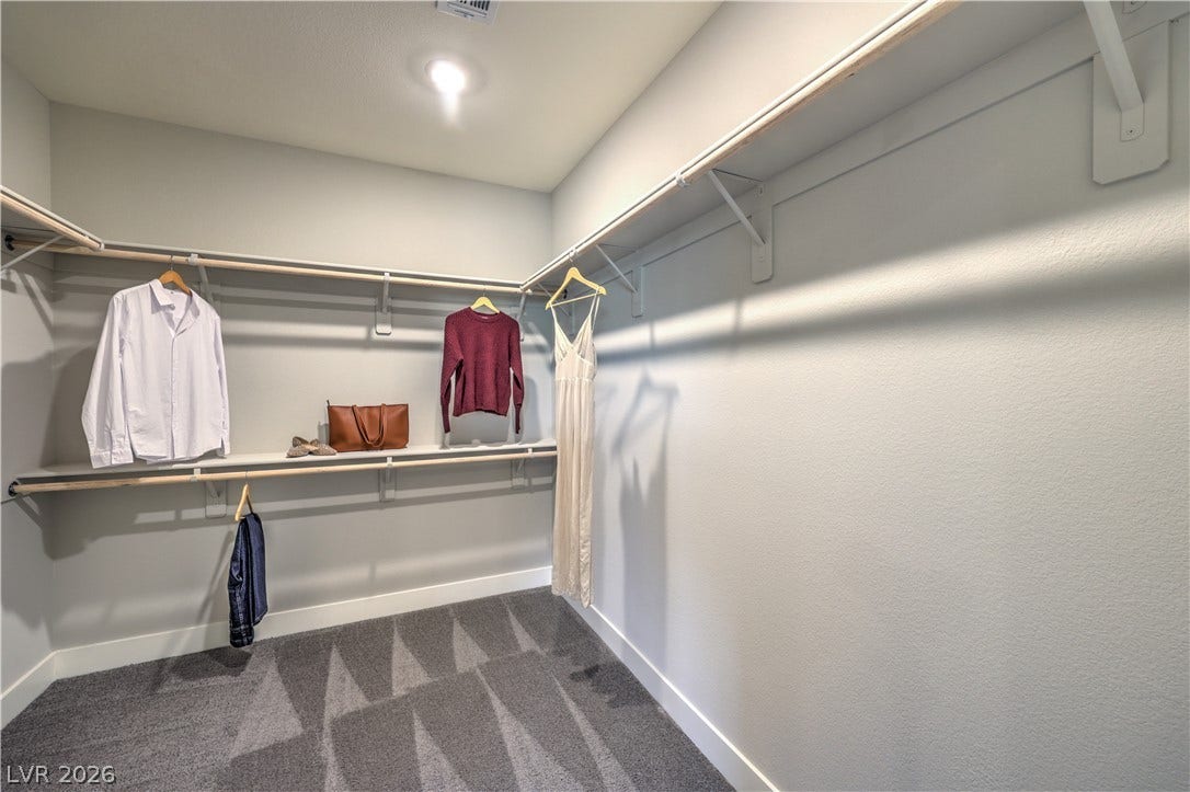 1044 Gentle Swan Street, Henderson, NV 89011 Ample hanging rods and built-in shelving wrap around this carpeted walk-in closet. Photo is of actual model home for sale.