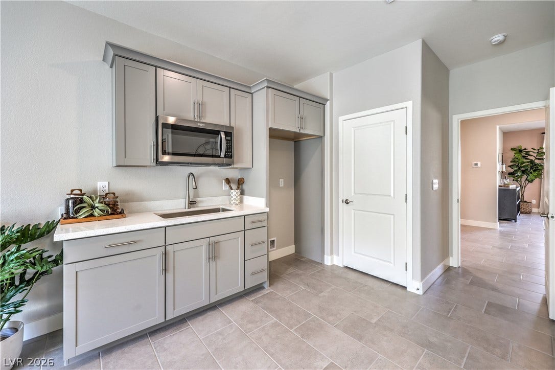 1044 Gentle Swan Street, Henderson, NV 89011 Sleek cabinetry and stone countertops elevate this modern kitchenette area with tile flooring.