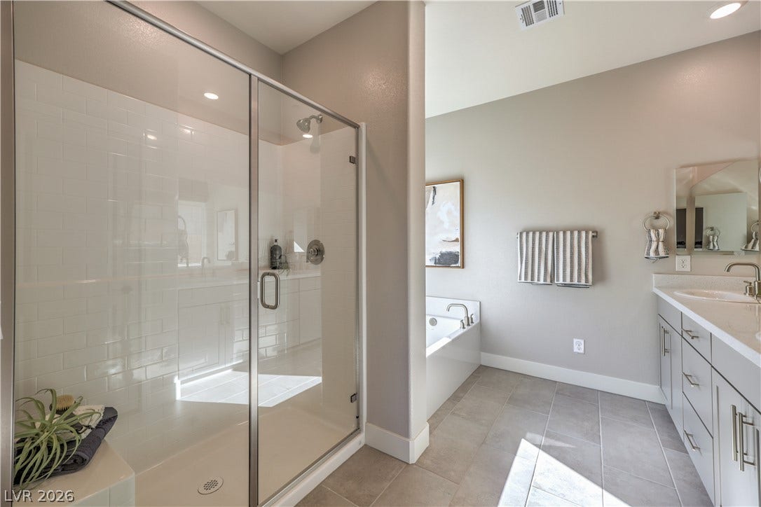 1044 Gentle Swan Street, Henderson, NV 89011 A glass-enclosed shower, deep soaking tub, and tile flooring define this modern bathroom space. Photo is of actual model home for sale.