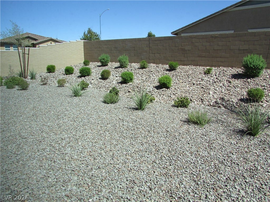 1044 Gentle Swan Street, Henderson, NV 89011 An enclosed desert landscape features a tiered rock garden along a solid masonry privacy wall. Photo is of actual model home for sale.