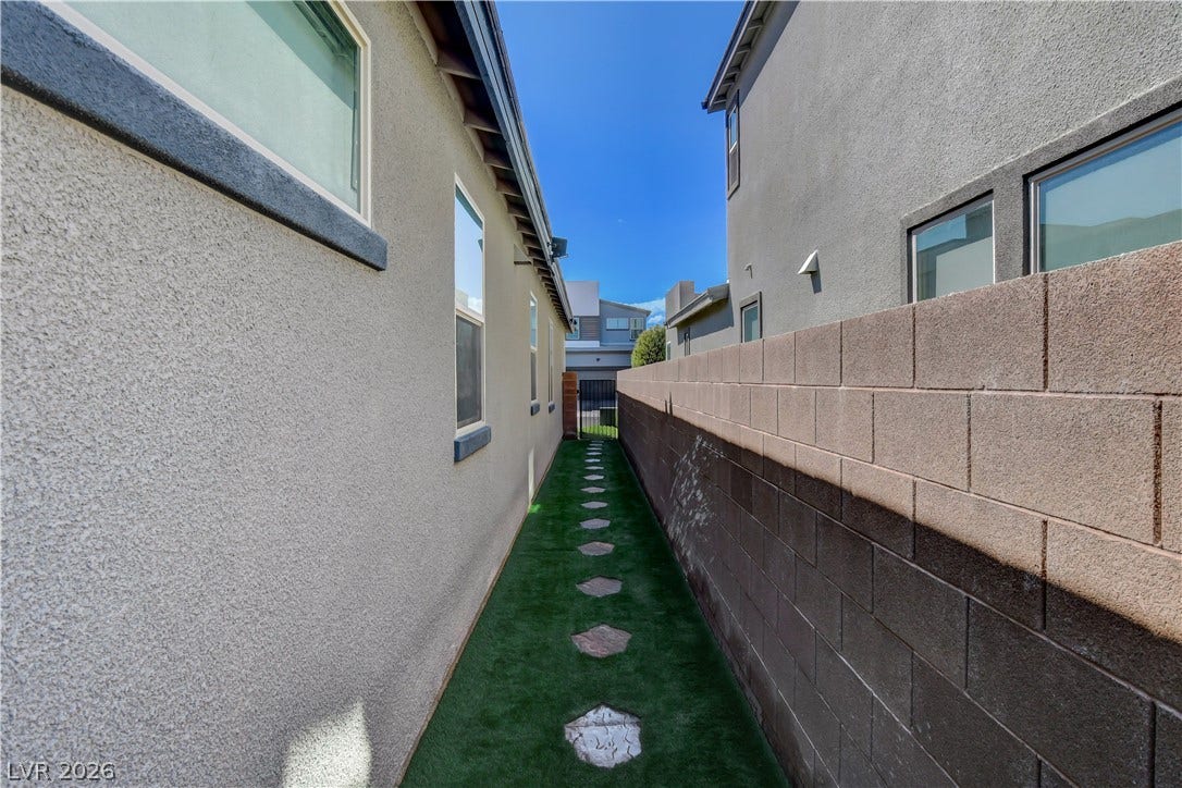 6834 Moorland Street, North Las Vegas, NV 89084 A stone pathway leads through the side yard flanked by a privacy block wall.
