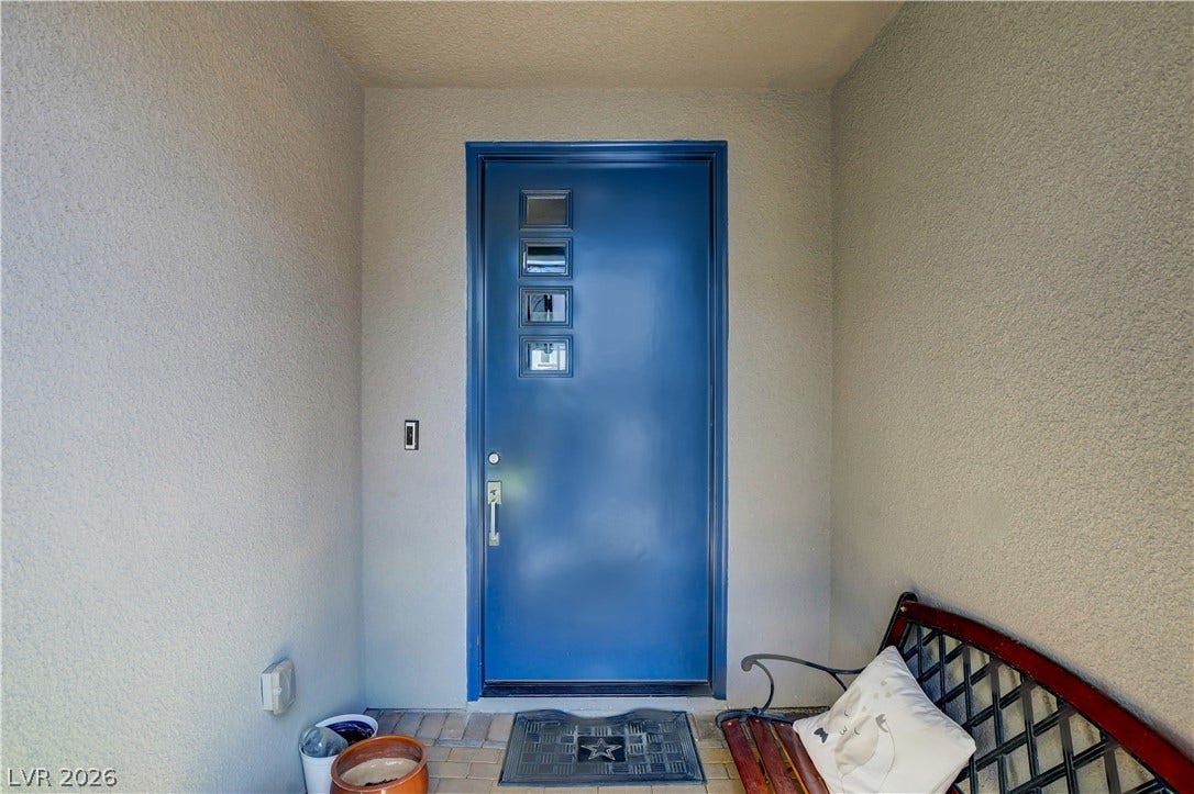 6834 Moorland Street, North Las Vegas, NV 89084 A recessed covered entryway leads to a modern front door with vertical window panes.
