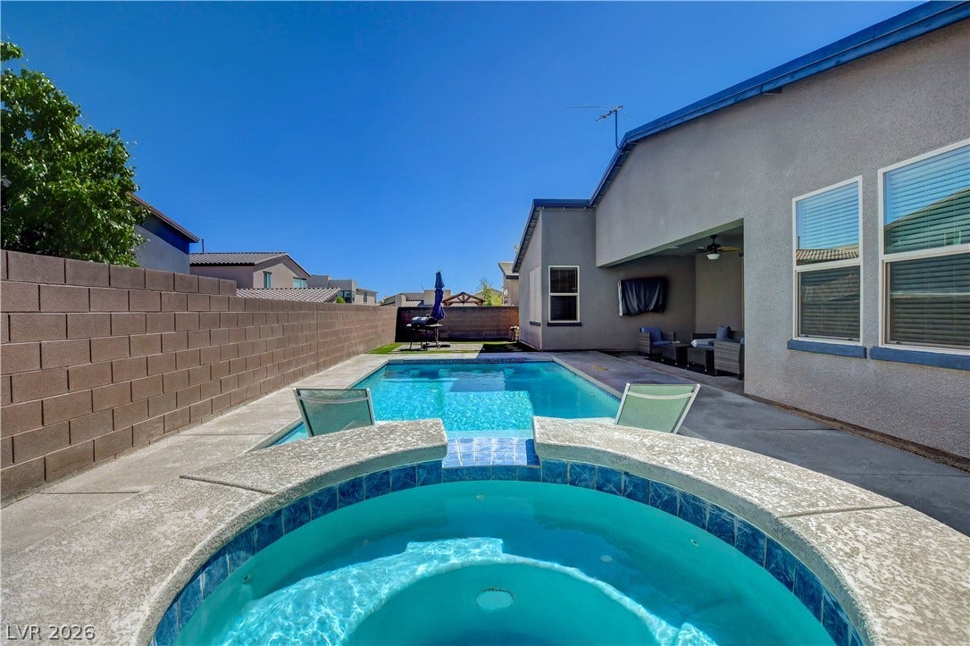 6834 Moorland Street, North Las Vegas, NV 89084 An inviting backyard oasis features a refreshing pool and integrated spa under clear blue skies.