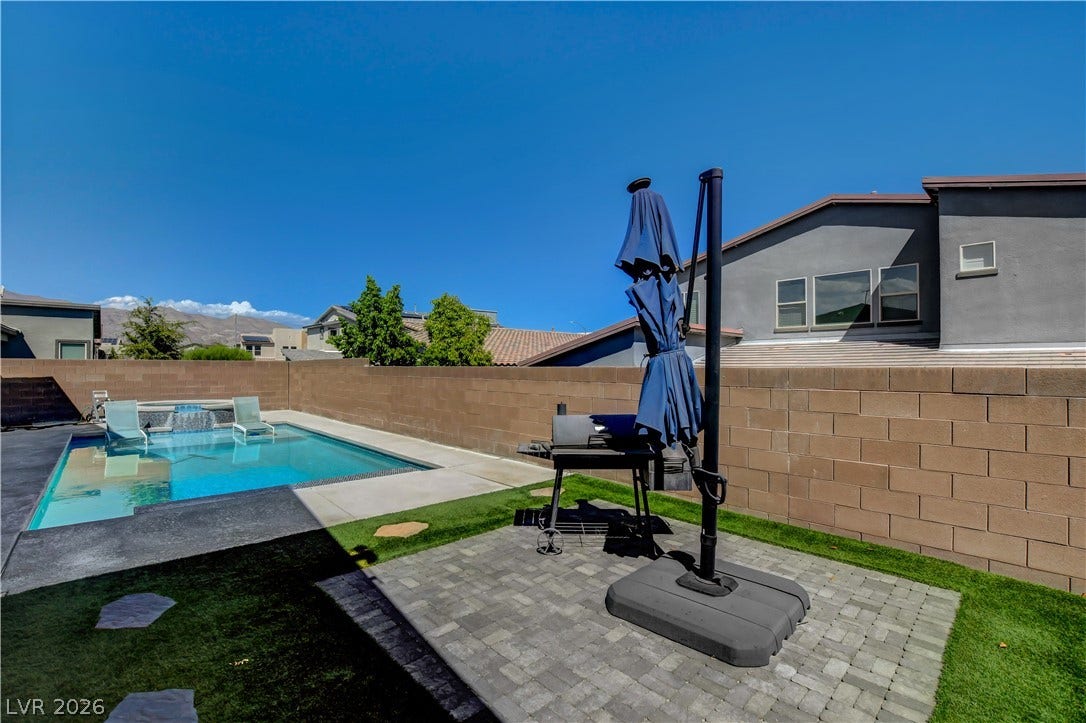 6834 Moorland Street, North Las Vegas, NV 89084 An inviting backyard oasis features a shimmering swimming pool surrounded by clean hardscaping and stone block walls.