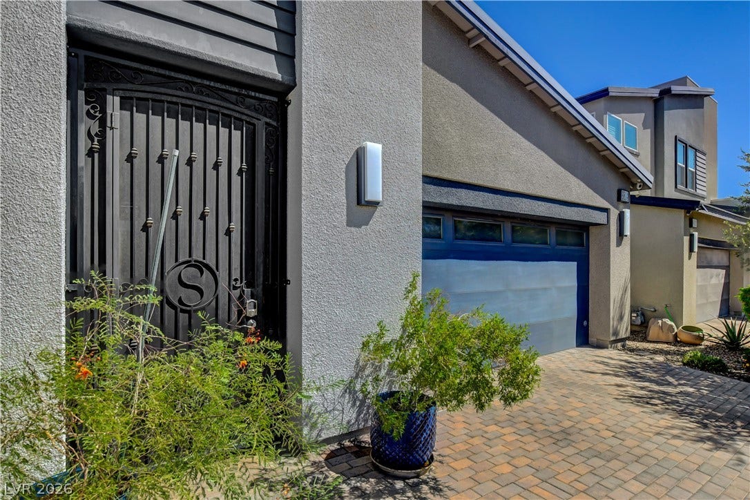 6834 Moorland Street, North Las Vegas, NV 89084 A secure wrought iron entry gate and stone paver driveway lead to the garage.