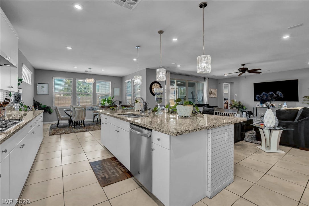 6834 Moorland Street, North Las Vegas, NV 89084 Granite countertops and white cabinetry define this airy kitchen opening to the main living areas.