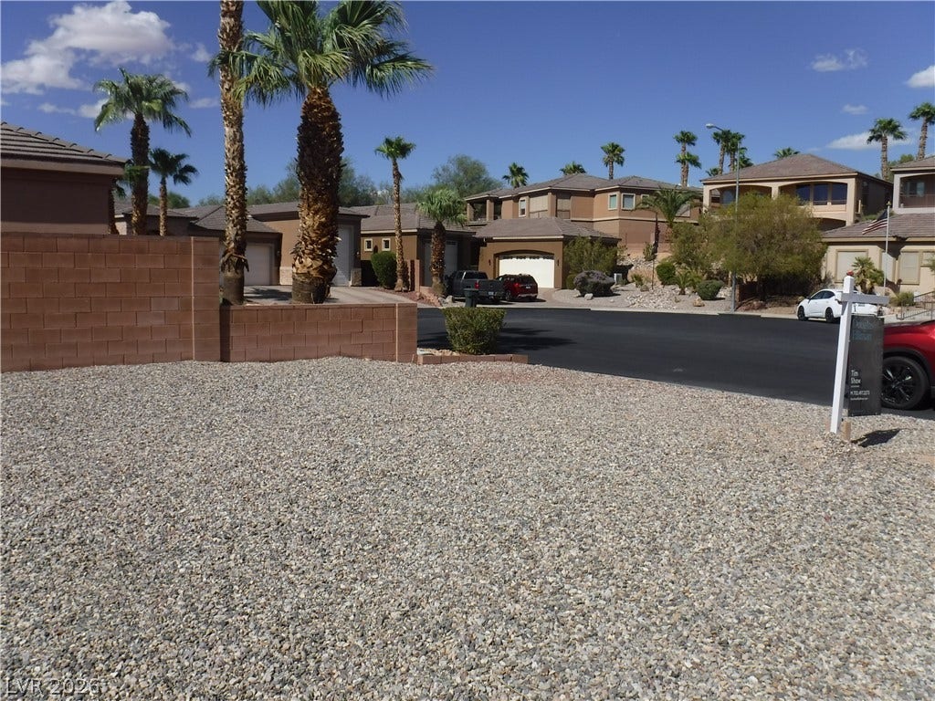 654 Paloma Circle, Mesquite, NV 89027 A gravel yard and low block walls sit under palm trees in a desert neighborhood.