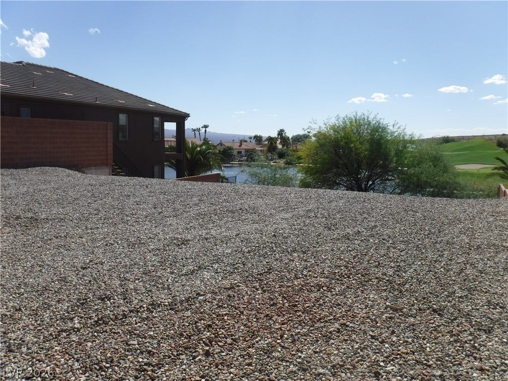 654 Paloma Circle, Mesquite, NV 89027 An open gravel yard overlooks a nearby waterway and rolling green hills.
