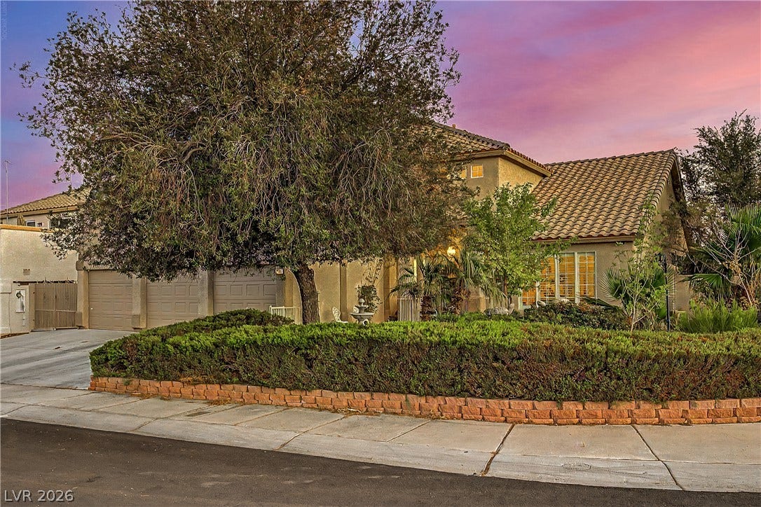 7741 Crenshaw Way, Las Vegas, NV 89129 Mature trees and neat landscaping frame this classic tile-roof residence under a warm sunset sky.