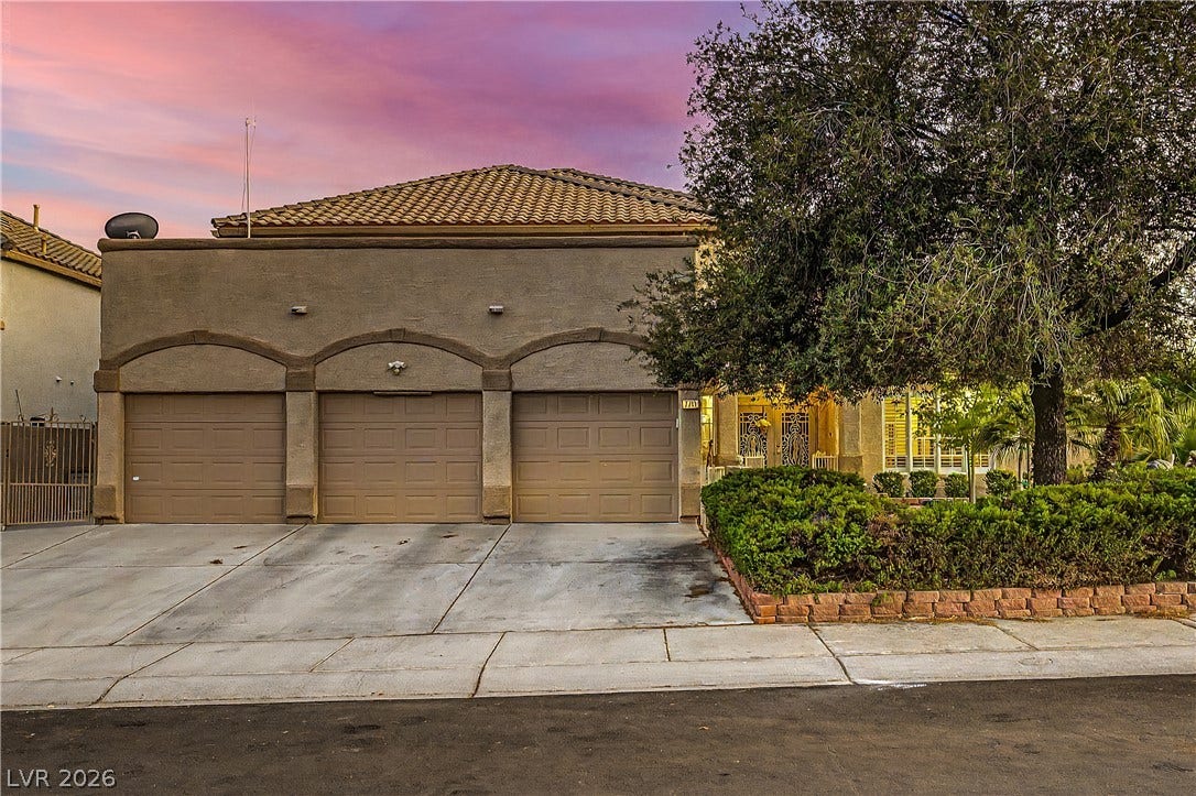 7741 Crenshaw Way, Las Vegas, NV 89129 A spacious driveway leads to three garage bays sheltered beneath a classic tile roof.
