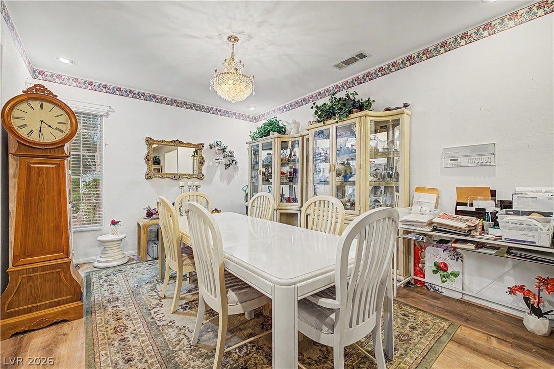 7741 Crenshaw Way, Las Vegas, NV 89129 An elegant chandelier highlights the formal dining room featuring wood floors and patterned wallpaper borders.