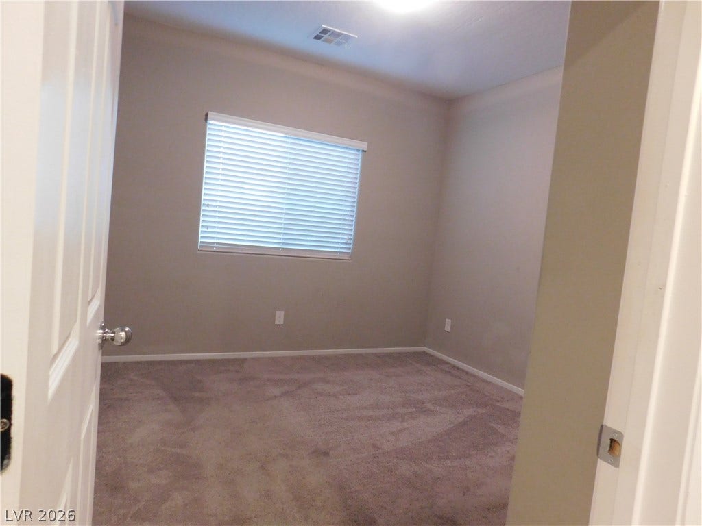 2715 Amazing Meadows Avenue, #1185, North Las Vegas, NV 89031 A window with horizontal blinds brings natural light into this carpeted bedroom.