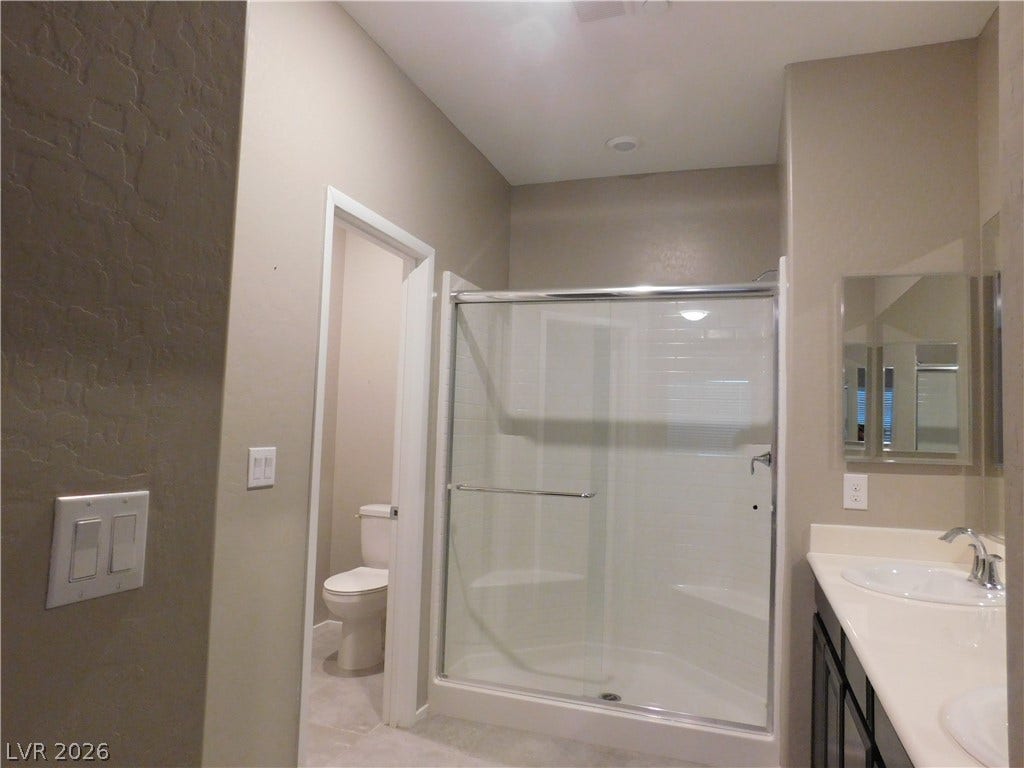 2715 Amazing Meadows Avenue, #1185, North Las Vegas, NV 89031 A classic bathroom layout includes a glass-door walk-in shower and a double vanity.