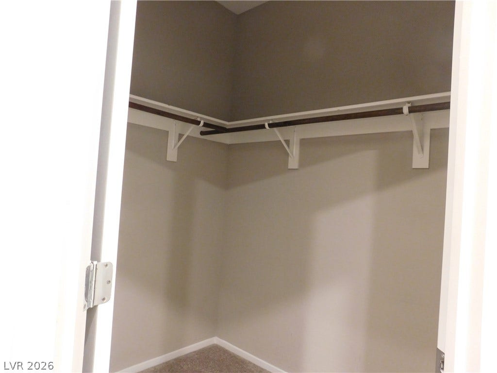 2715 Amazing Meadows Avenue, #1185, North Las Vegas, NV 89031 A spacious walk-in closet includes carpet flooring and built-in shelving with hanging rods.