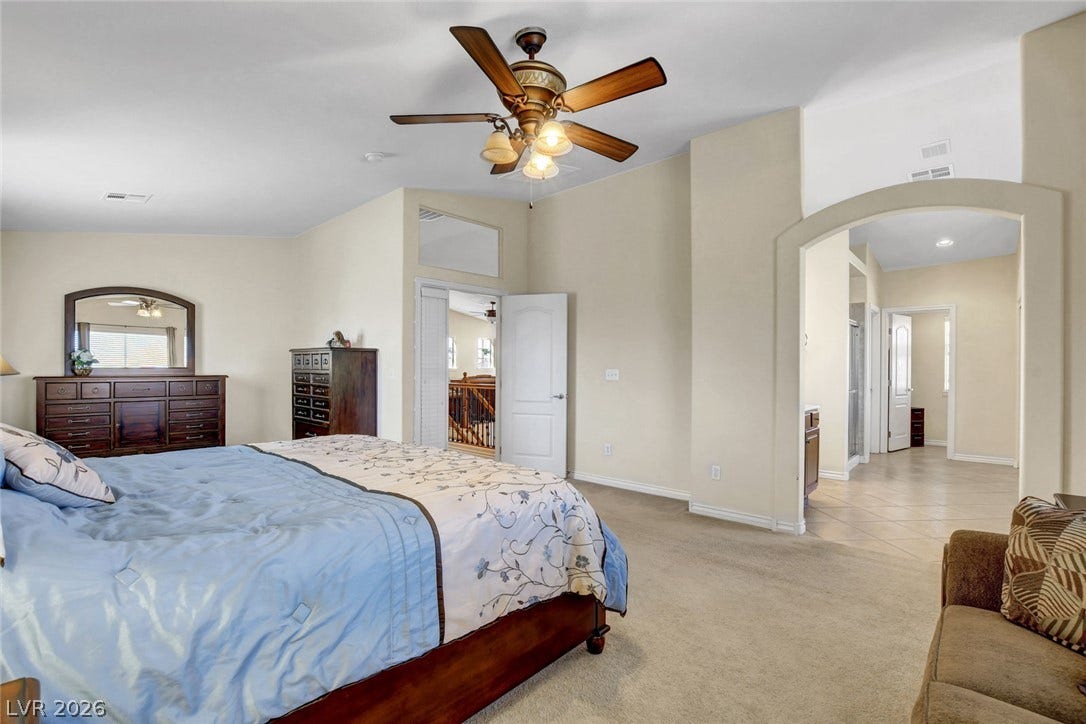5508 Meridian Rain Street, North Las Vegas, NV 89031 A spacious bedroom features neutral carpeting, an arched doorway, and an attached master bath.
