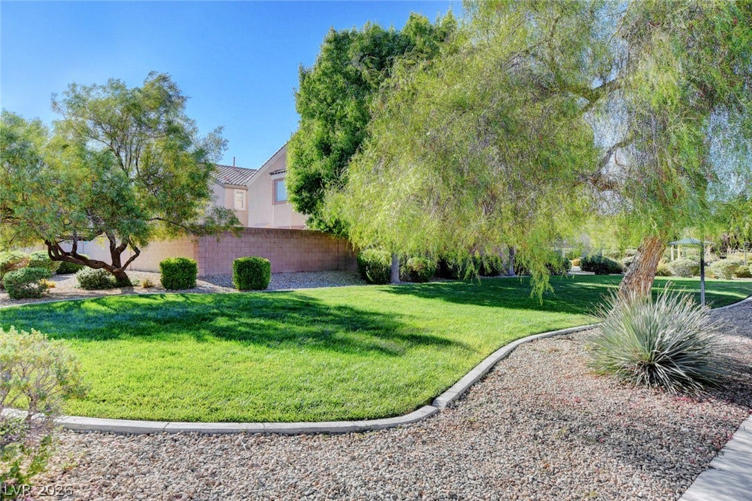 5508 Meridian Rain Street, North Las Vegas, NV 89031 Mature shade trees and a manicured green lawn highlight this serene outdoor space.