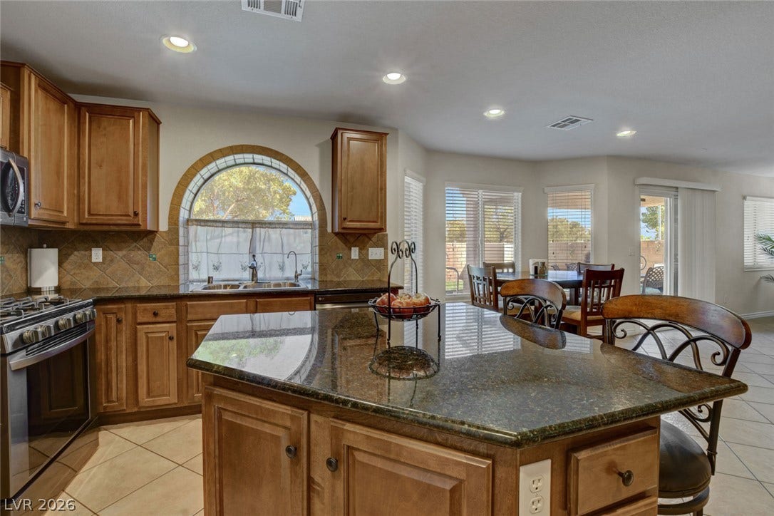 5508 Meridian Rain Street, North Las Vegas, NV 89031 Polished granite countertops and classic wooden cabinetry elevate this open kitchen design.