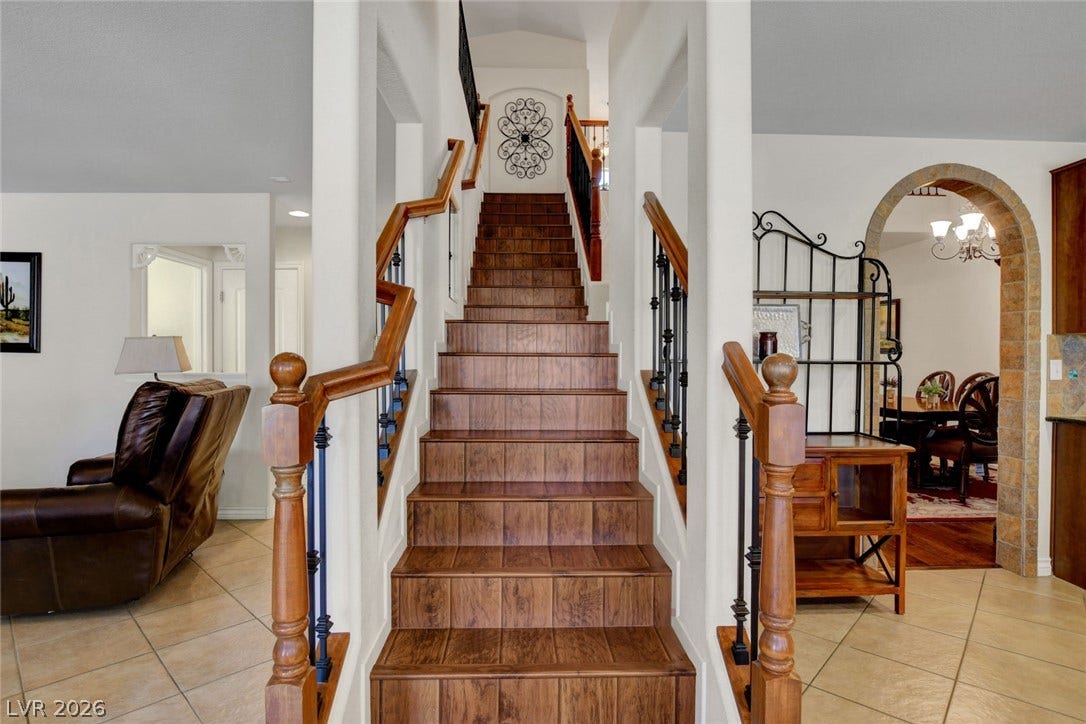 5508 Meridian Rain Street, North Las Vegas, NV 89031 Rich wood stairs rise elegantly, flanked by warm tile flooring and classic arched entries.
