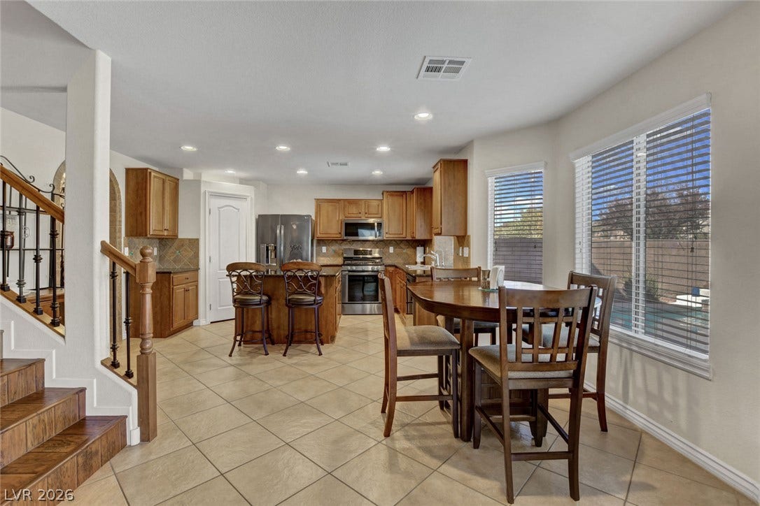 5508 Meridian Rain Street, North Las Vegas, NV 89031 Tiled flooring flows through an open-concept kitchen and adjacent dining area flanked by large windows.