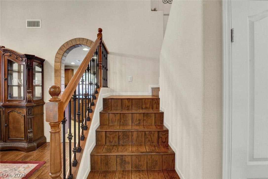 5508 Meridian Rain Street, North Las Vegas, NV 89031 Rich wood stairs climb past an elegant arched doorway framed in decorative tile work.