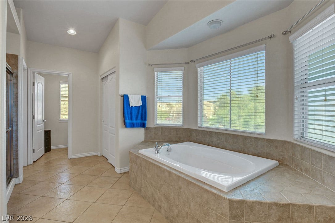 5508 Meridian Rain Street, North Las Vegas, NV 89031 An inviting soaking tub rests beneath large windows in this tiled bathroom.