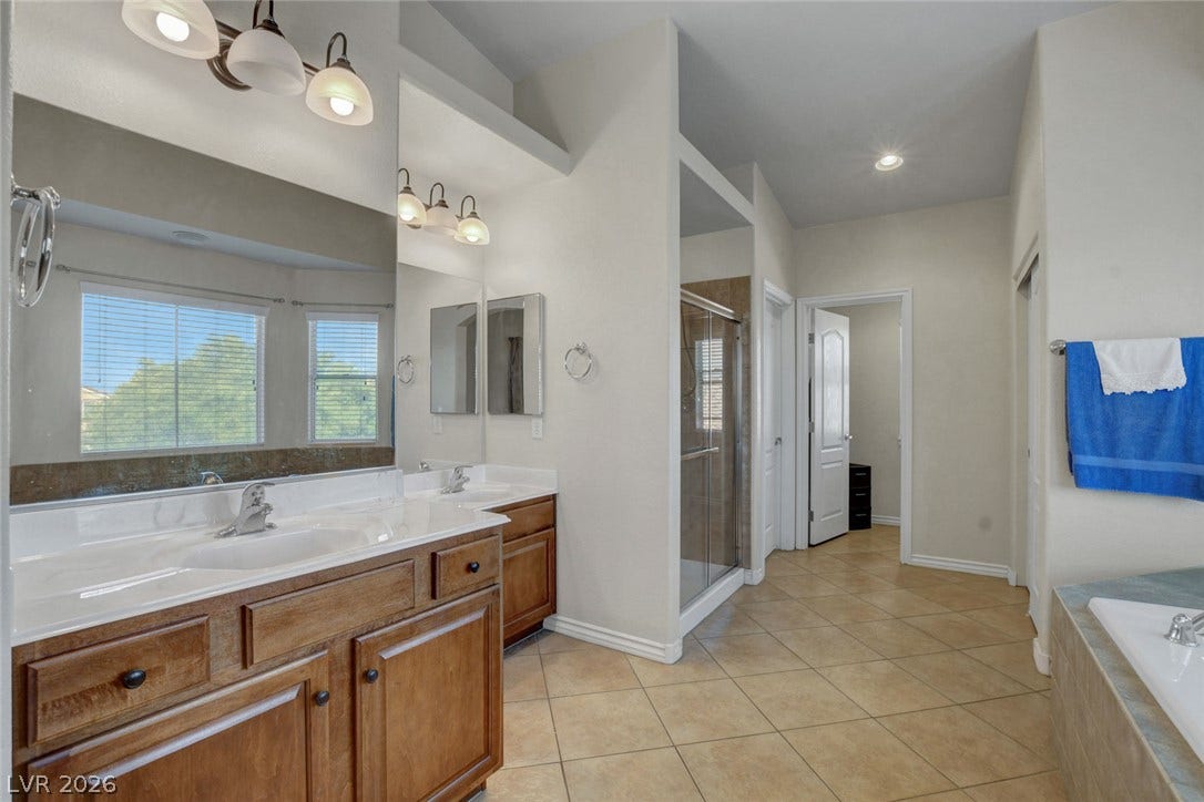 5508 Meridian Rain Street, North Las Vegas, NV 89031 A spacious layout showcases dual vanities, neutral tiling, and a separate glass-enclosed shower.