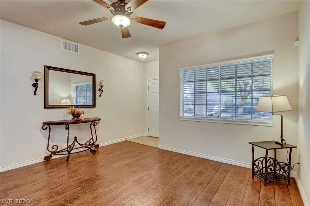 5508 Meridian Rain Street, North Las Vegas, NV 89031 Rich wood-look flooring and a wide window with blinds define this inviting living space.