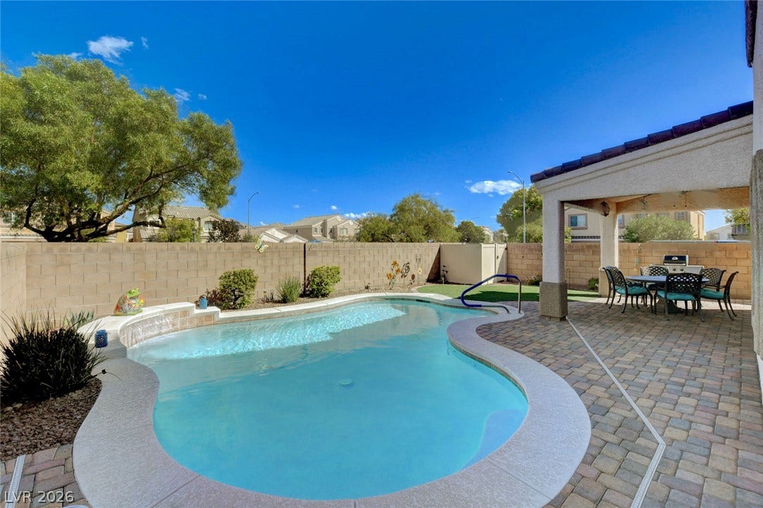5508 Meridian Rain Street, North Las Vegas, NV 89031 An inviting backyard features a curved swimming pool alongside a covered paver patio.