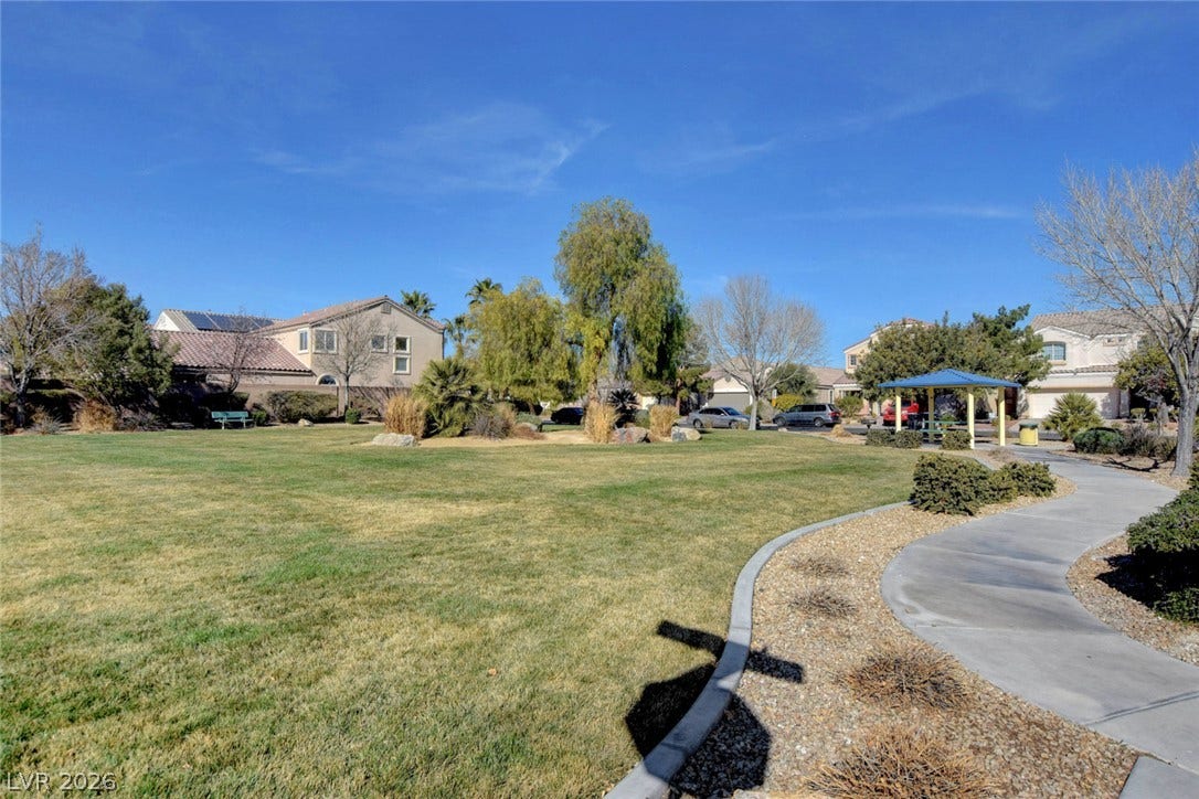 5508 Meridian Rain Street, North Las Vegas, NV 89031 A paved walking path winds through a peaceful neighborhood green space under clear blue skies.