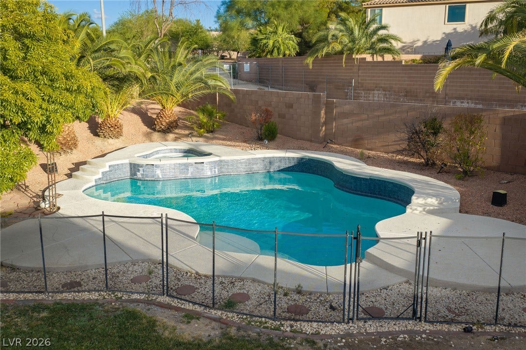 2381 Predera Avenue, Henderson, NV 89052 A private swimming pool and integrated spa sit surrounded by protective fencing and desert landscaping.