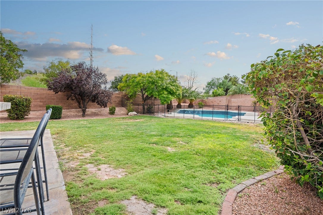 2381 Predera Avenue, Henderson, NV 89052 Lush grassy grounds stretch toward a fenced private swimming pool under open skies.