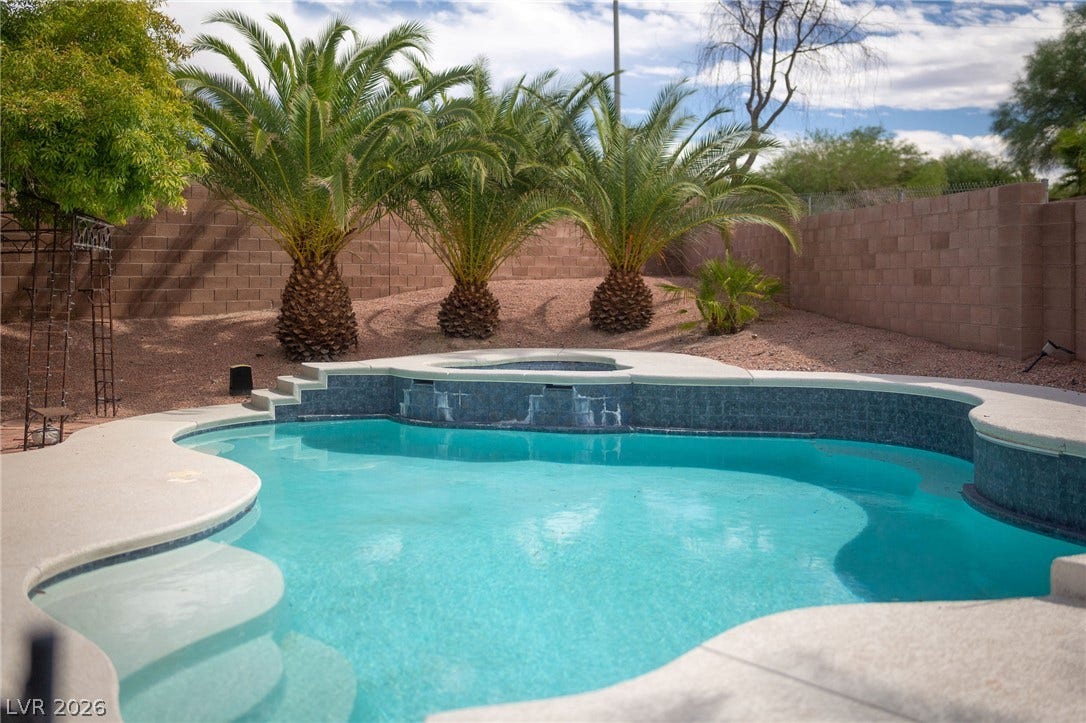 2381 Predera Avenue, Henderson, NV 89052 Mature palm trees frame a sparkling swimming pool within a fully fenced backyard oasis.