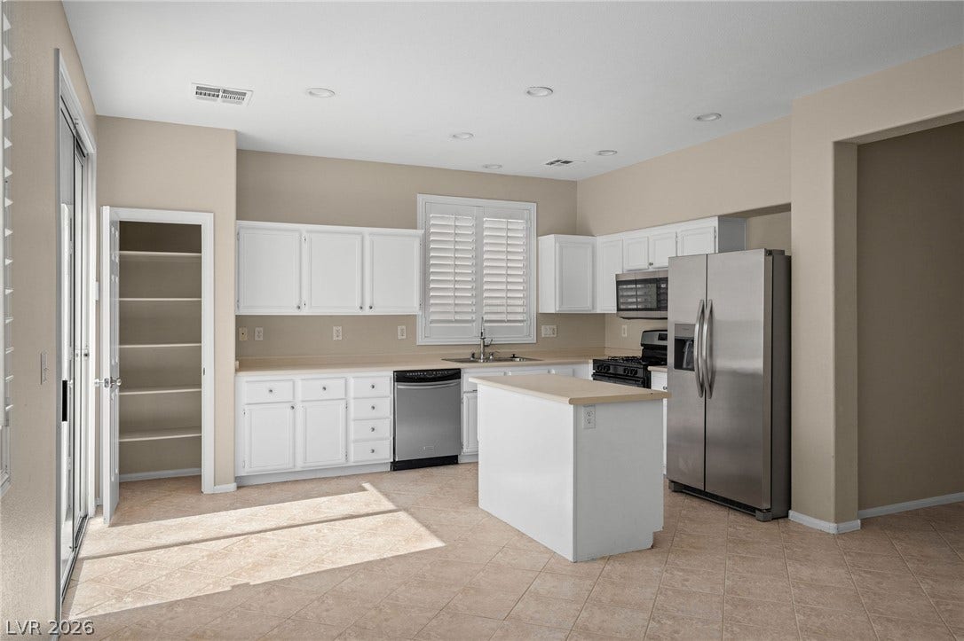 2381 Predera Avenue, Henderson, NV 89052 White cabinetry, solid surface countertops, and tile flooring define this bright, functional kitchen space.