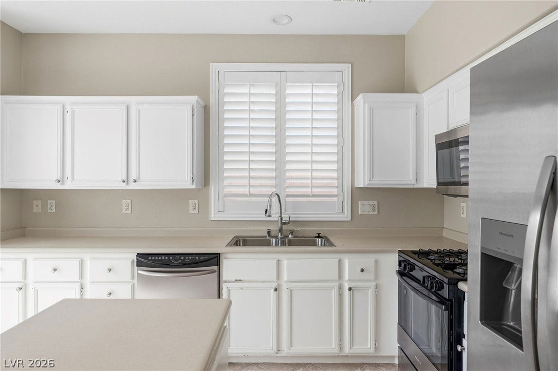 2381 Predera Avenue, Henderson, NV 89052 White cabinetry, solid surface countertops, and stainless steel appliances define this functional culinary space.