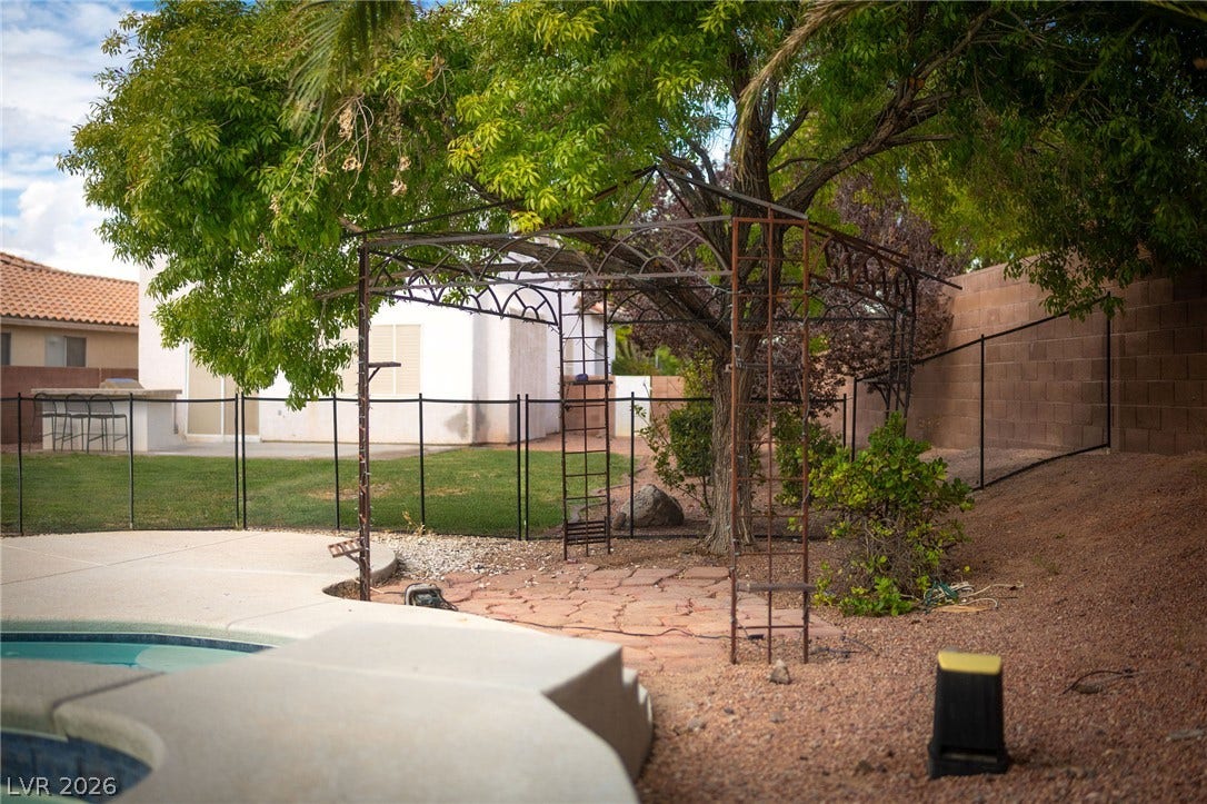2381 Predera Avenue, Henderson, NV 89052 Mature trees shade a paved patio area adjacent to the backyard swimming pool.