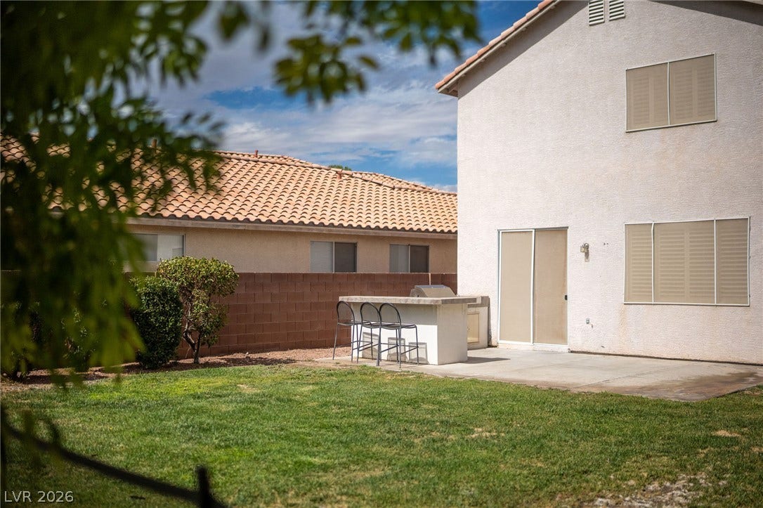 2381 Predera Avenue, Henderson, NV 89052 A spacious lawn anchors this private backyard featuring a concrete patio and built-in barbecue island.