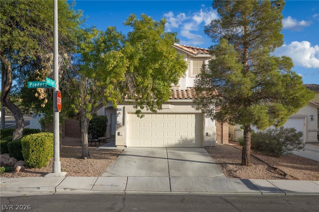 2381 Predera Avenue, Henderson, NV 89052 Mature trees flank a concrete driveway leading to a two-story home with tiled roofing.