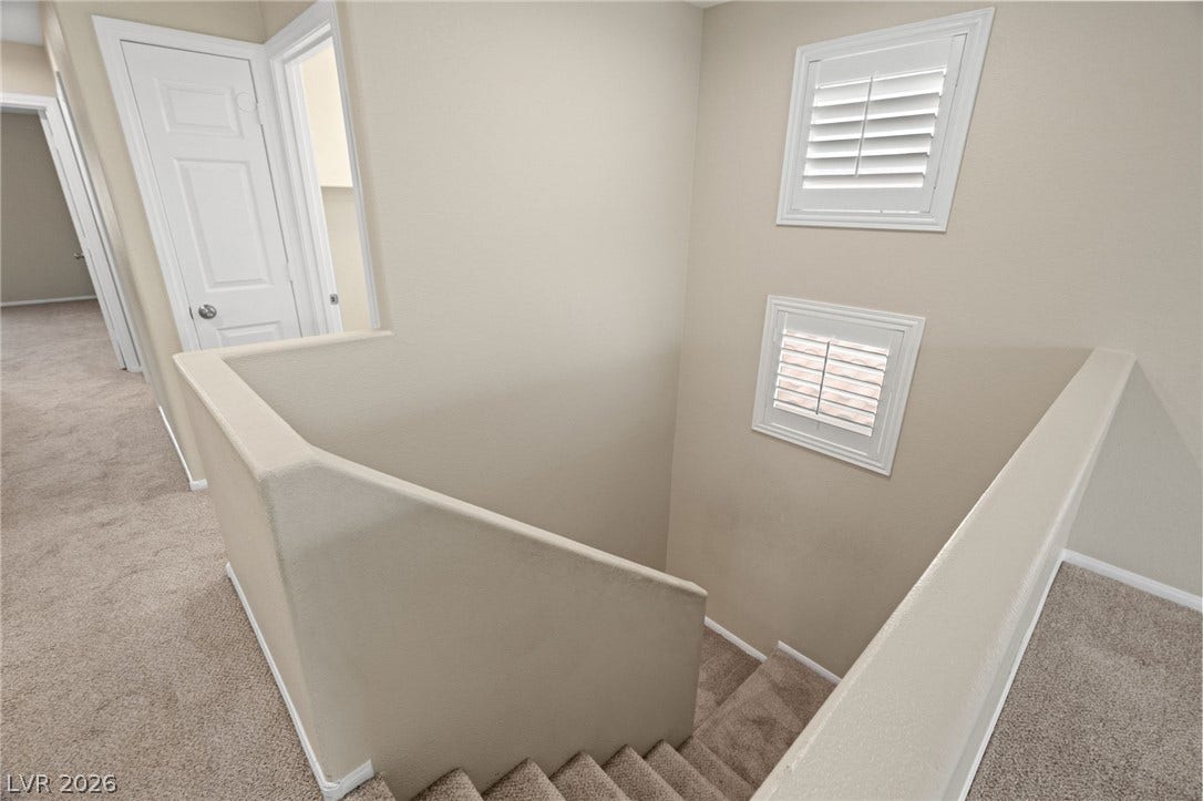 2381 Predera Avenue, Henderson, NV 89052 Carpeted stairs descend from an upper level hallway flanked by shuttered interior windows.