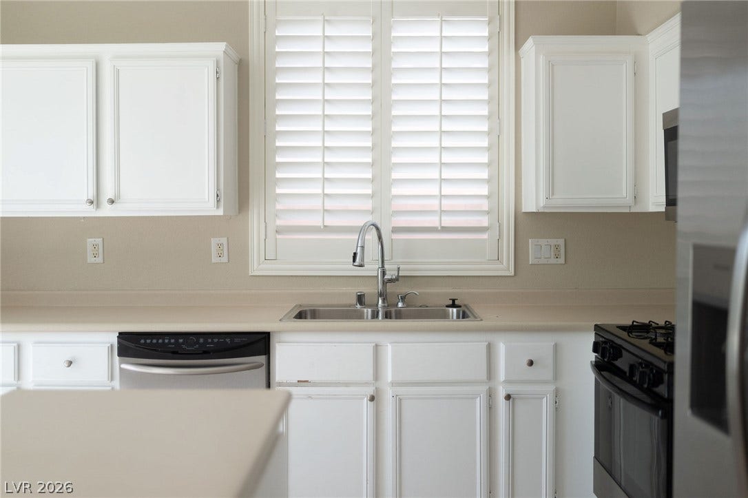 2381 Predera Avenue, Henderson, NV 89052 Crisp white cabinetry and modern stainless steel appliances define this functional kitchen workspace.
