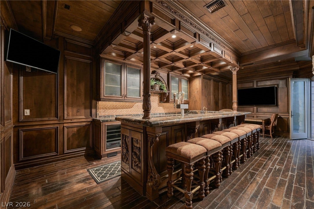 1513 Foothills Village Drive, Henderson, NV 89012 Rich wood paneling, an ornate coffered ceiling, and detailed cabinetry elevate this custom home bar.