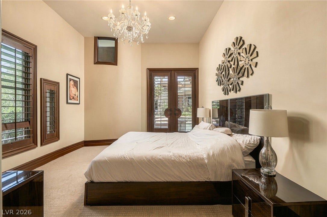 1513 Foothills Village Drive, Henderson, NV 89012 A spacious bedroom features plush carpeting, towering ceilings, and an elegant crystal chandelier.