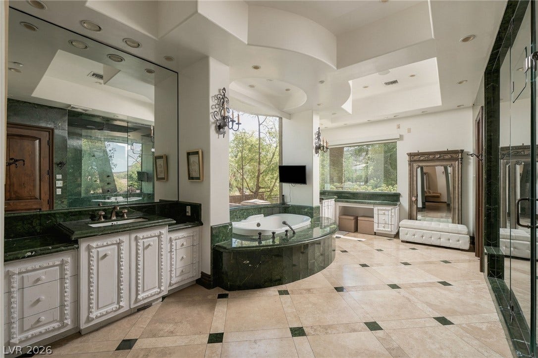 1513 Foothills Village Drive, Henderson, NV 89012 Polished stone flooring and matching custom vanities frame a deep soaking tub.