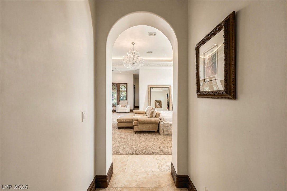 1513 Foothills Village Drive, Henderson, NV 89012 An arched doorway frames the transition from tiled hall to a carpeted living space.
