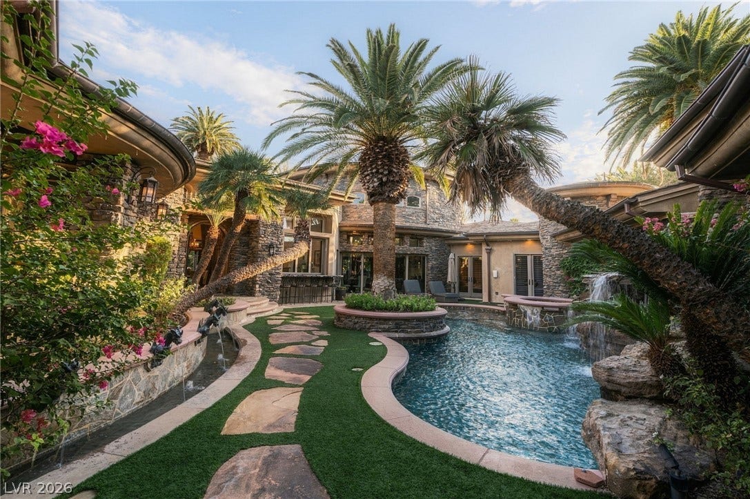 1513 Foothills Village Drive, Henderson, NV 89012 An inviting backyard oasis showcases stone construction, a winding pool, and lush palm landscaping.