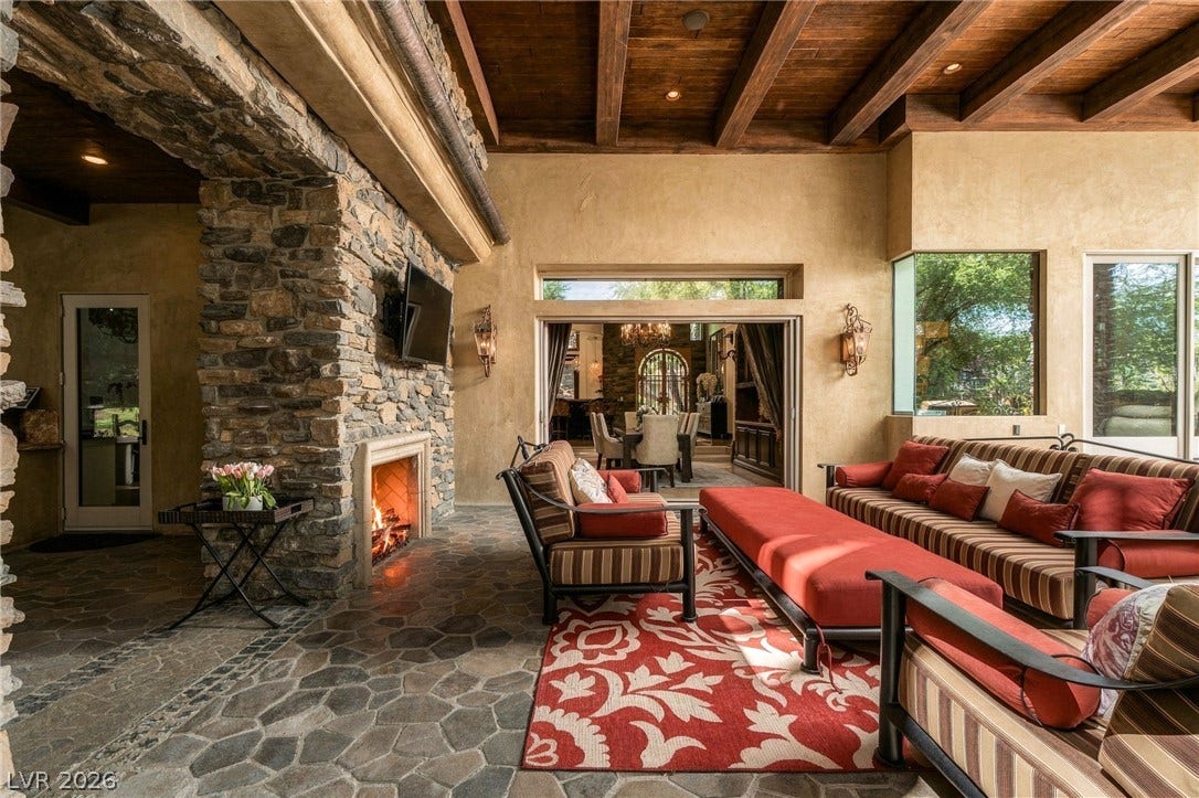 1513 Foothills Village Drive, Henderson, NV 89012 Rich wood-beamed ceilings and a majestic stone fireplace anchor this warm, inviting covered living space.