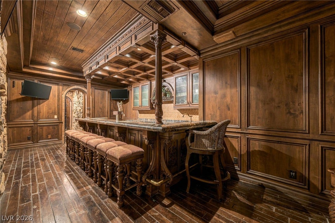 1513 Foothills Village Drive, Henderson, NV 89012 Ornate wood paneling and stone accents enclose a custom wet bar with detailed timber ceilings.