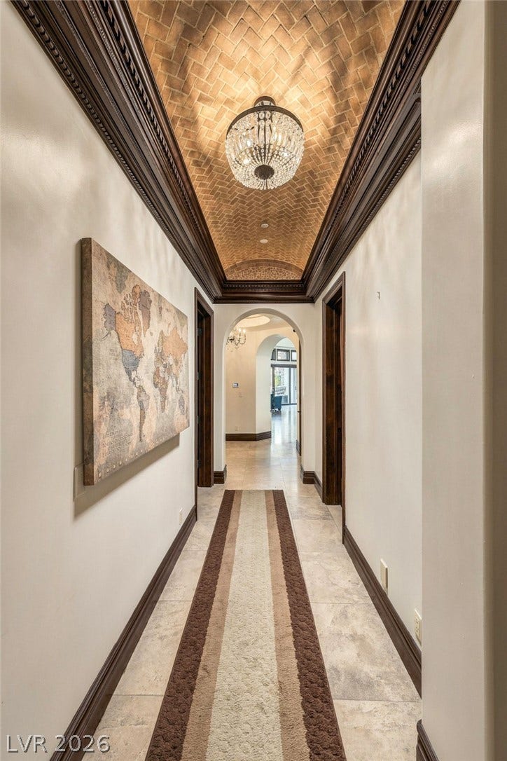 1513 Foothills Village Drive, Henderson, NV 89012 An arched brick ceiling with custom wood molding frames a long stone-tiled hallway.