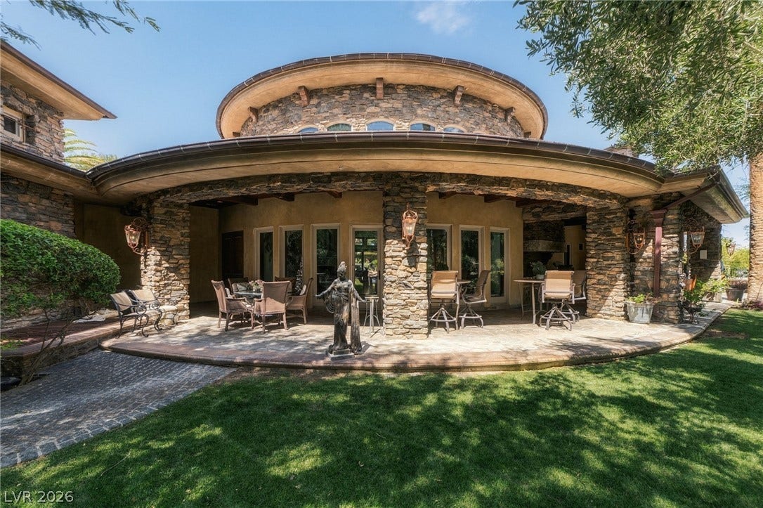 1513 Foothills Village Drive, Henderson, NV 89012 An expansive covered stone patio overlooks a manicured grassy lawn.