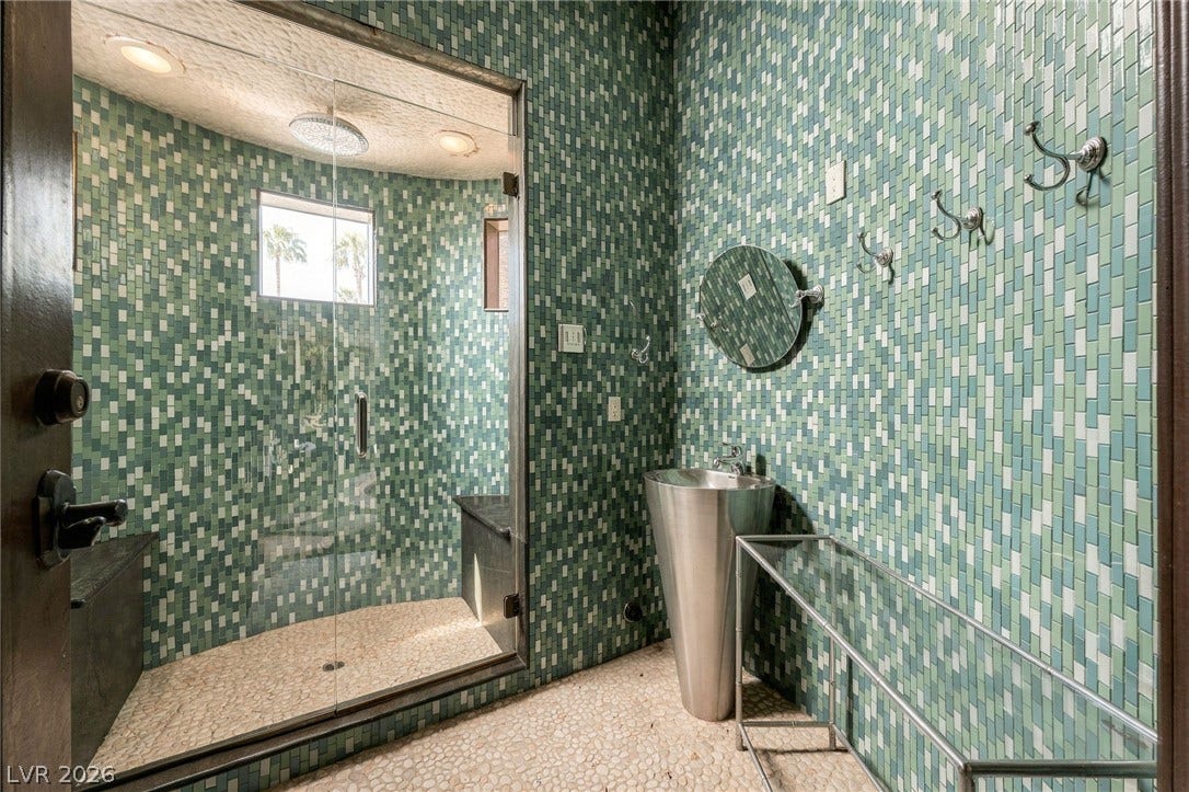 1513 Foothills Village Drive, Henderson, NV 89012 Floor-to-ceiling mosaic tilework and a glass-enclosed walk-in shower define this modern bathroom space.